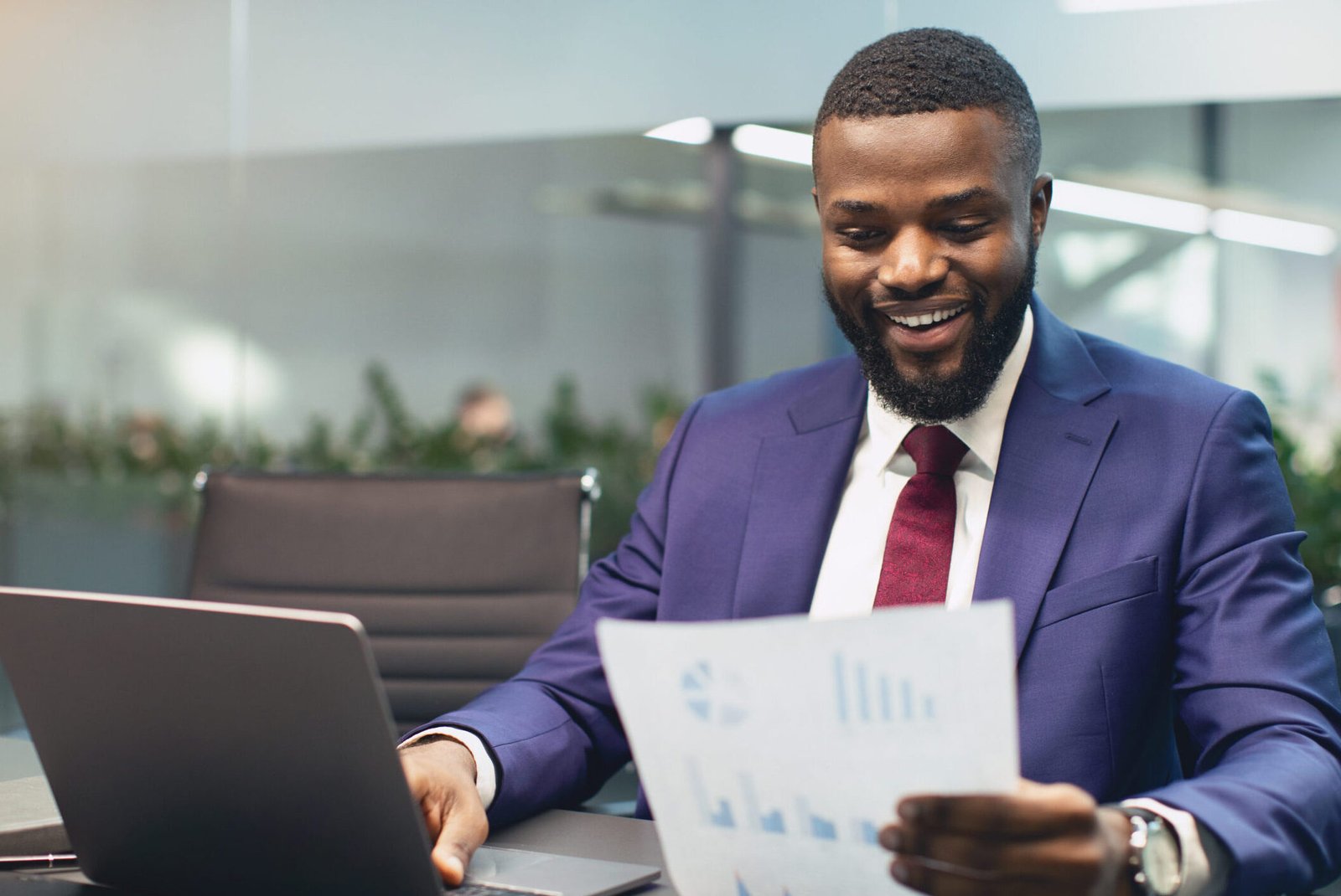 Smiling black businessman checking reports in modern office